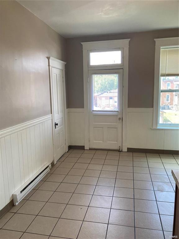 doorway with light tile patterned floors and a baseboard heating unit