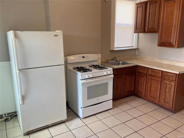 kitchen with light tile patterned flooring, white appliances, and sink