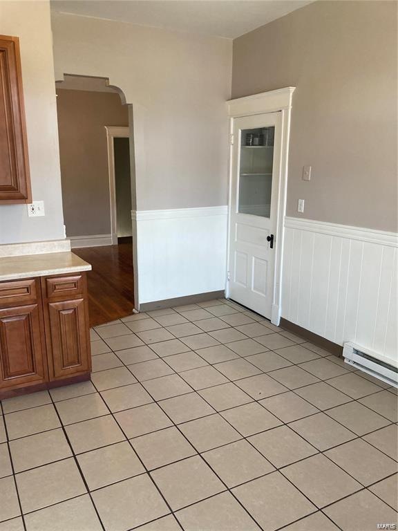 unfurnished room with light tile patterned floors and a baseboard radiator