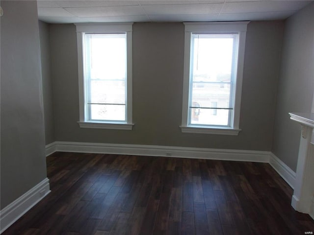 unfurnished room with dark hardwood / wood-style floors and a drop ceiling