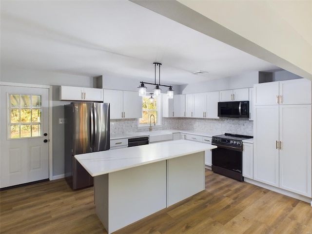 kitchen featuring a healthy amount of sunlight, a center island, black appliances, and decorative light fixtures