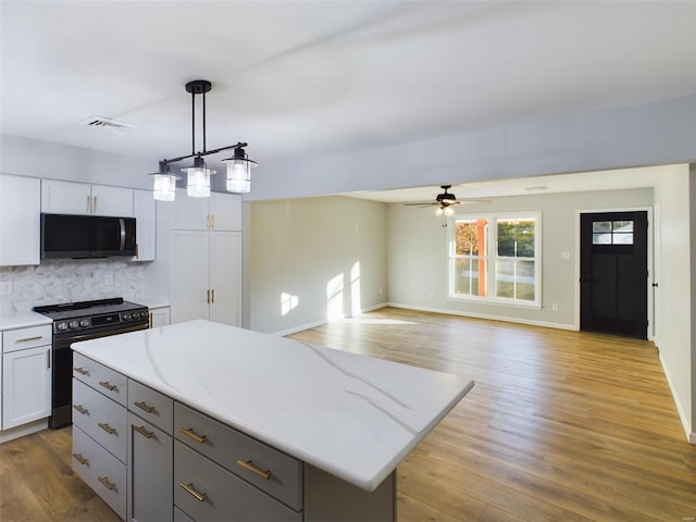 kitchen featuring a center island, black electric range oven, light hardwood / wood-style floors, and hanging light fixtures