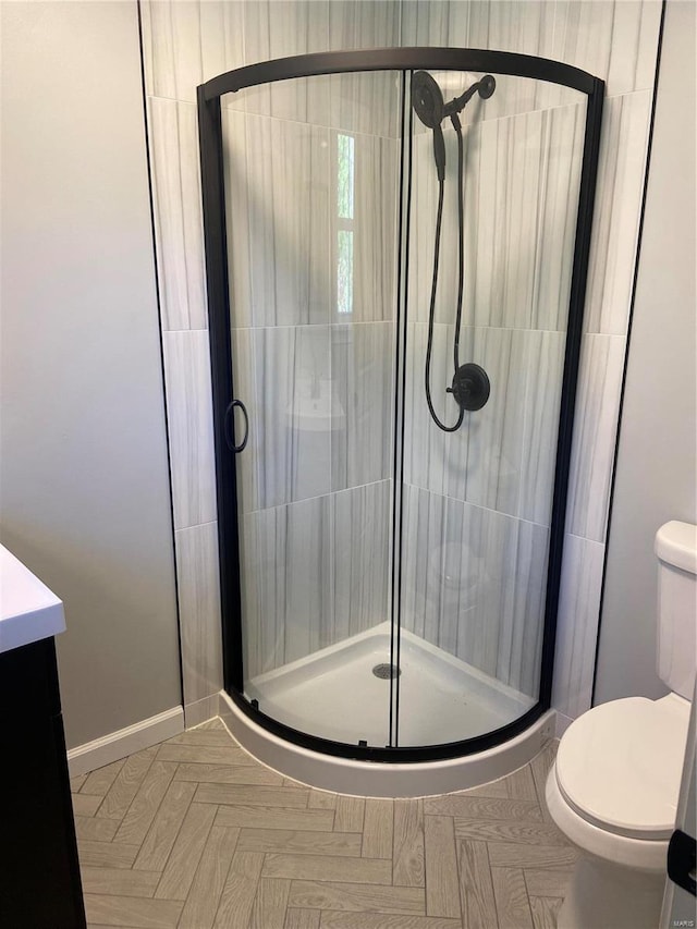 bathroom featuring parquet flooring, vanity, toilet, and a shower with shower door