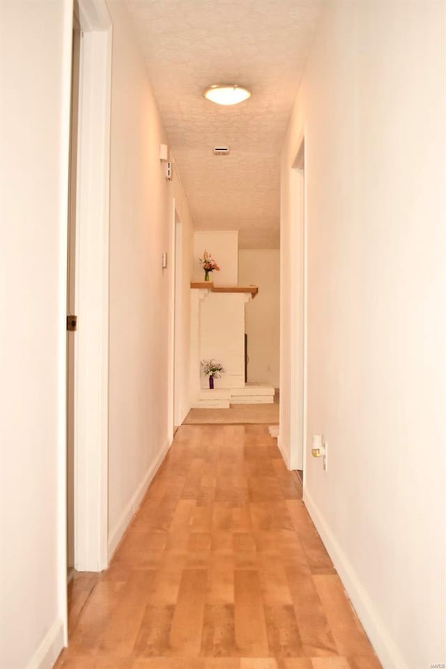 hallway featuring light hardwood / wood-style flooring and a textured ceiling