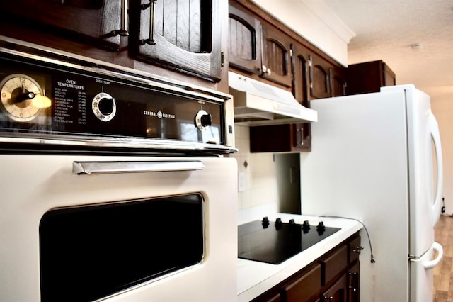 kitchen with dark brown cabinetry, black appliances, and ornamental molding