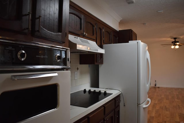 kitchen featuring black appliances, dark brown cabinets, decorative backsplash, and a textured ceiling