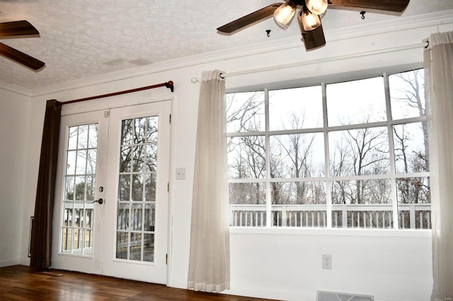 doorway with a textured ceiling, crown molding, dark wood-type flooring, and french doors