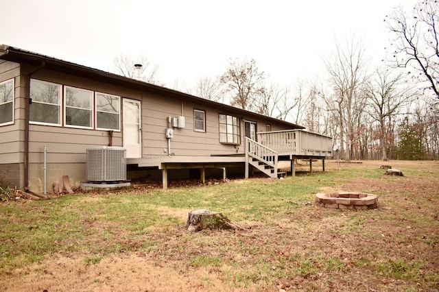 rear view of property featuring a lawn, central AC, a fire pit, and a deck