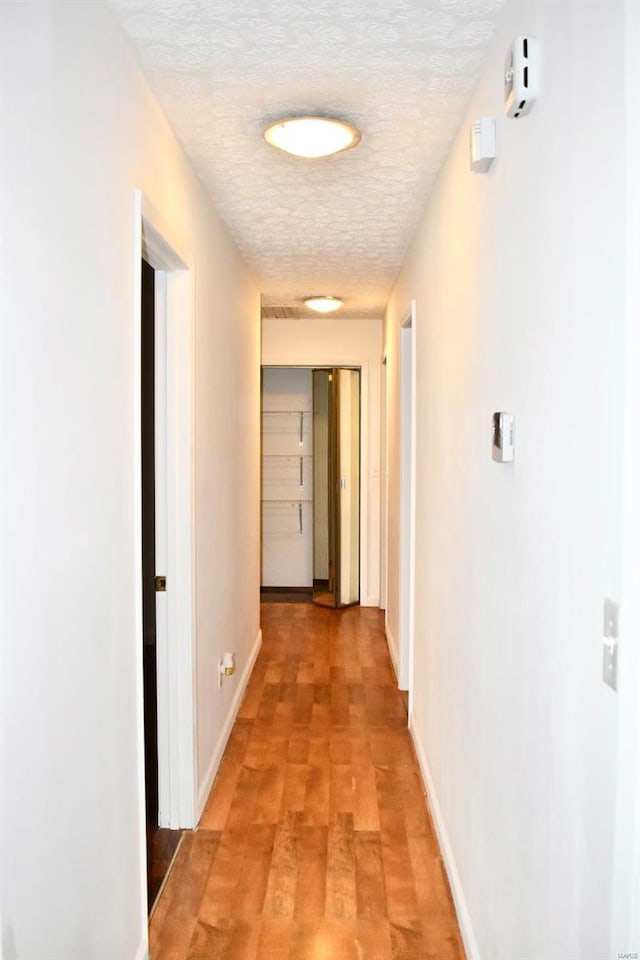 hall with hardwood / wood-style flooring and a textured ceiling