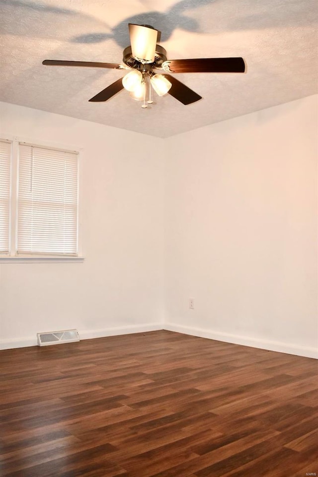 empty room featuring ceiling fan, dark hardwood / wood-style flooring, and a textured ceiling