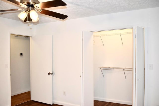 unfurnished bedroom with a textured ceiling, ceiling fan, and dark wood-type flooring