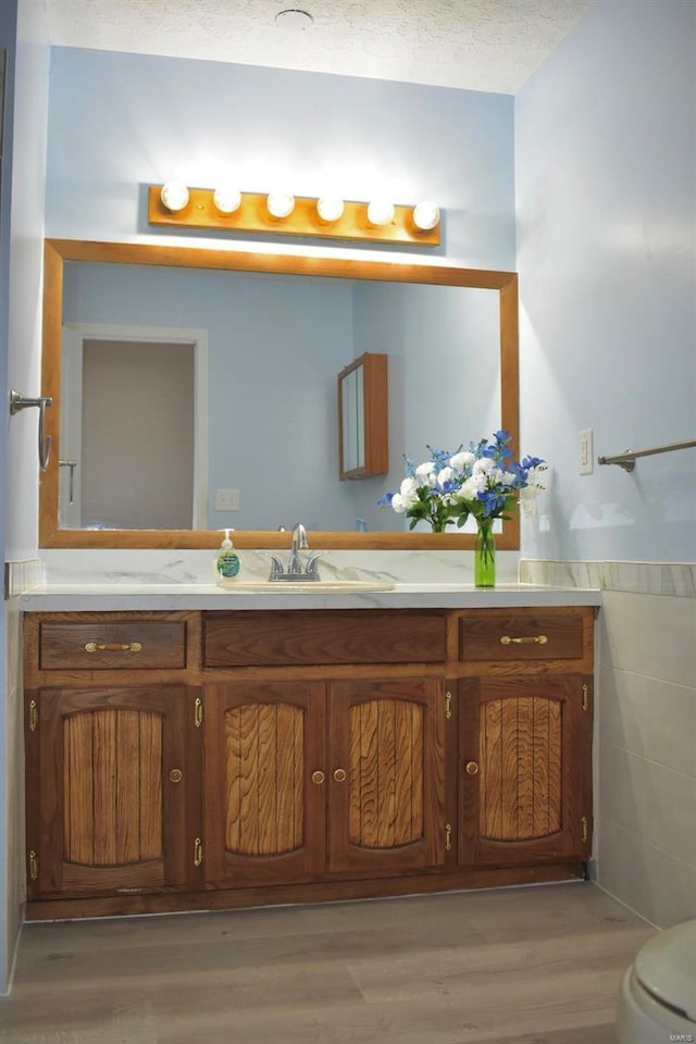 bathroom featuring vanity, wood-type flooring, a textured ceiling, and toilet