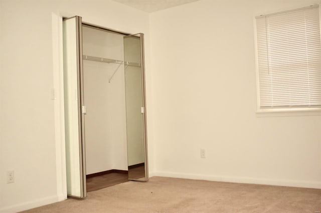 unfurnished bedroom featuring light colored carpet and a closet