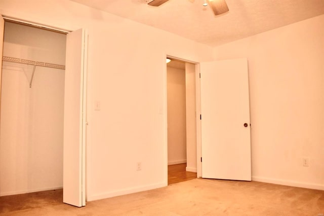 unfurnished bedroom with light carpet, a closet, and ceiling fan