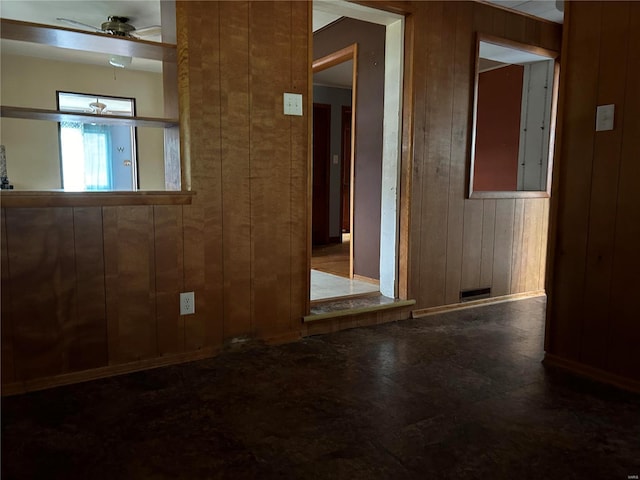 unfurnished room with ceiling fan and wooden walls