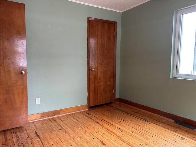 empty room featuring crown molding and light hardwood / wood-style flooring