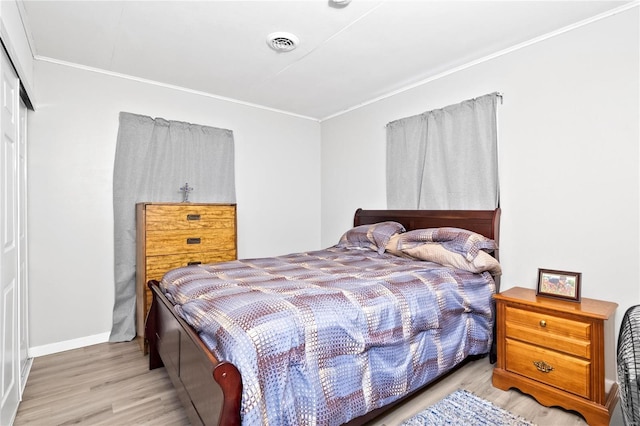 bedroom with light hardwood / wood-style floors, crown molding, and a closet