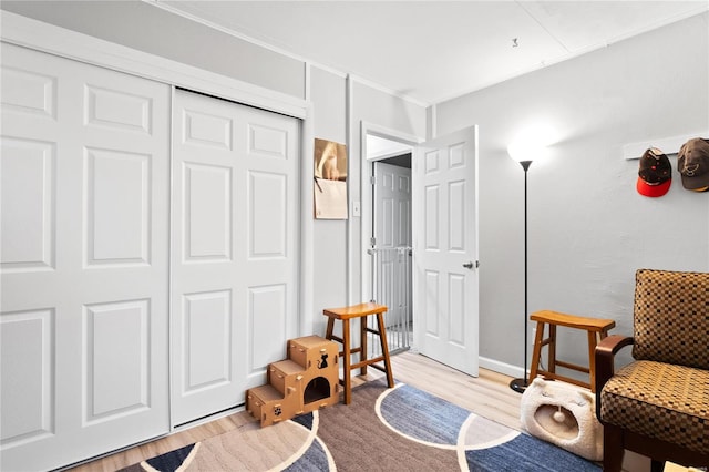 sitting room featuring crown molding and light hardwood / wood-style flooring