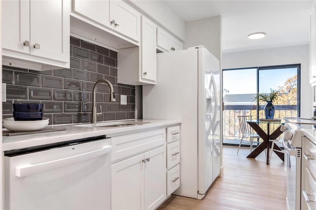 kitchen with sink, white cabinets, light hardwood / wood-style floors, and white appliances