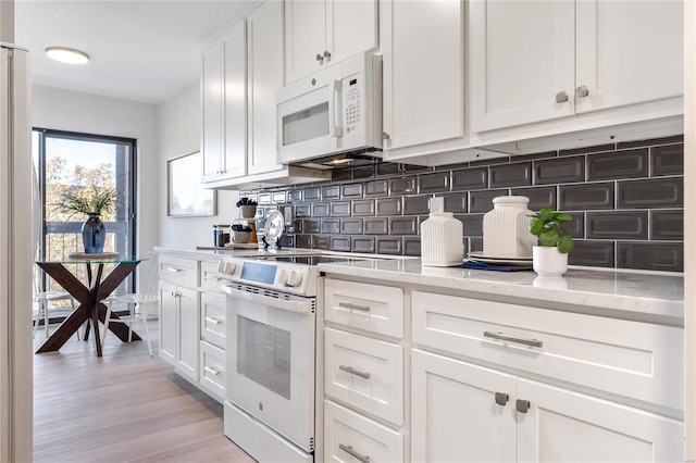 kitchen with light wood-type flooring, white appliances, white cabinetry, and light stone counters