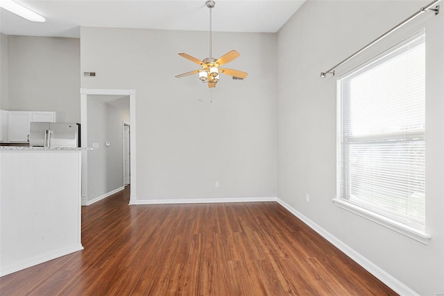 spare room featuring a wealth of natural light, ceiling fan, and dark wood-type flooring