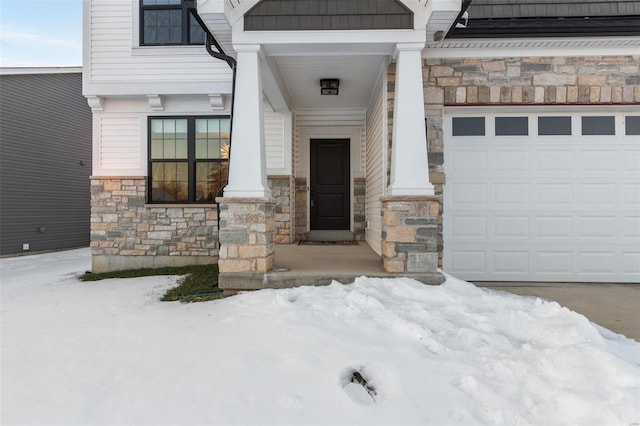 snow covered property entrance featuring a garage