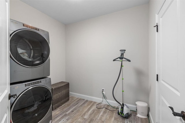 washroom with light hardwood / wood-style floors and stacked washer / drying machine