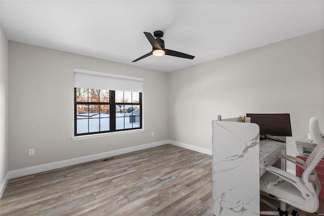 unfurnished office with ceiling fan and light wood-type flooring