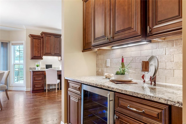 kitchen featuring wine cooler, ornamental molding, light stone counters, tasteful backsplash, and dark hardwood / wood-style flooring