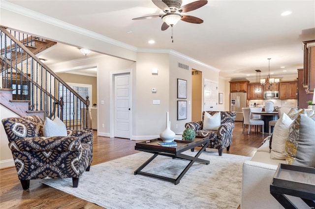 living room featuring dark hardwood / wood-style floors, ceiling fan with notable chandelier, and ornamental molding