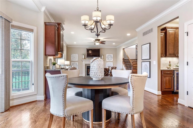 dining area with ceiling fan with notable chandelier, dark hardwood / wood-style floors, wine cooler, and crown molding