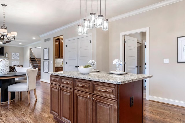 kitchen with dark wood-type flooring, hanging light fixtures, ornamental molding, a kitchen island, and a chandelier