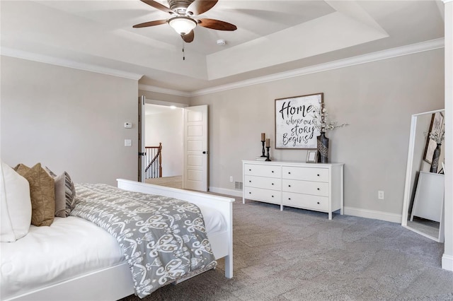 carpeted bedroom featuring a tray ceiling, ceiling fan, and crown molding