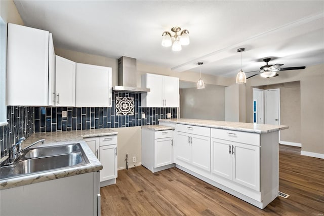 kitchen featuring white cabinets, light hardwood / wood-style floors, kitchen peninsula, and sink