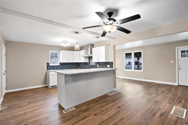 kitchen featuring tasteful backsplash, dark wood-type flooring, wall chimney range hood, white cabinets, and hanging light fixtures