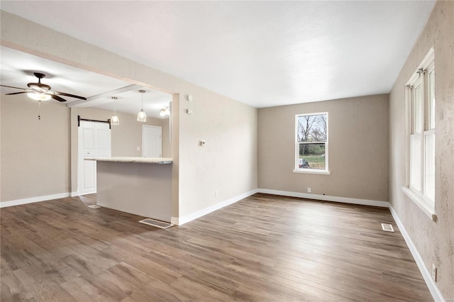 unfurnished room featuring a barn door, dark hardwood / wood-style floors, and ceiling fan