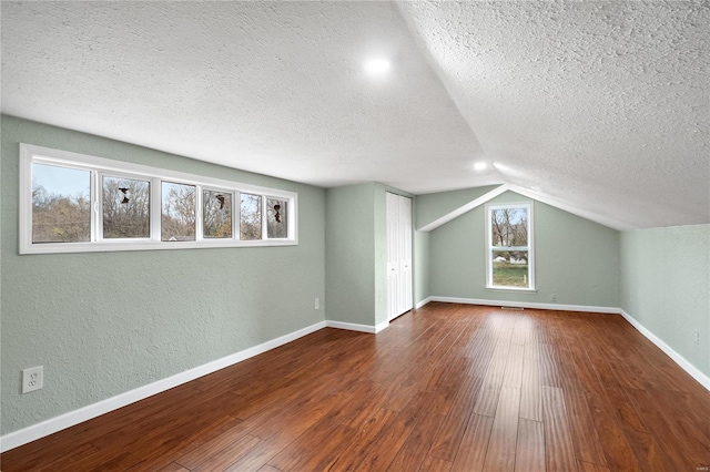 additional living space with a textured ceiling, hardwood / wood-style flooring, and a wealth of natural light