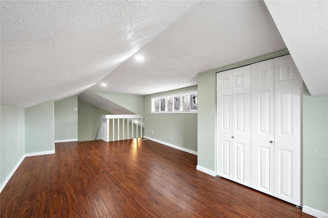 bonus room featuring vaulted ceiling, wood-type flooring, and a textured ceiling