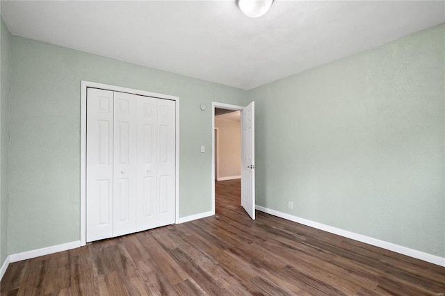 unfurnished bedroom featuring a closet and dark wood-type flooring