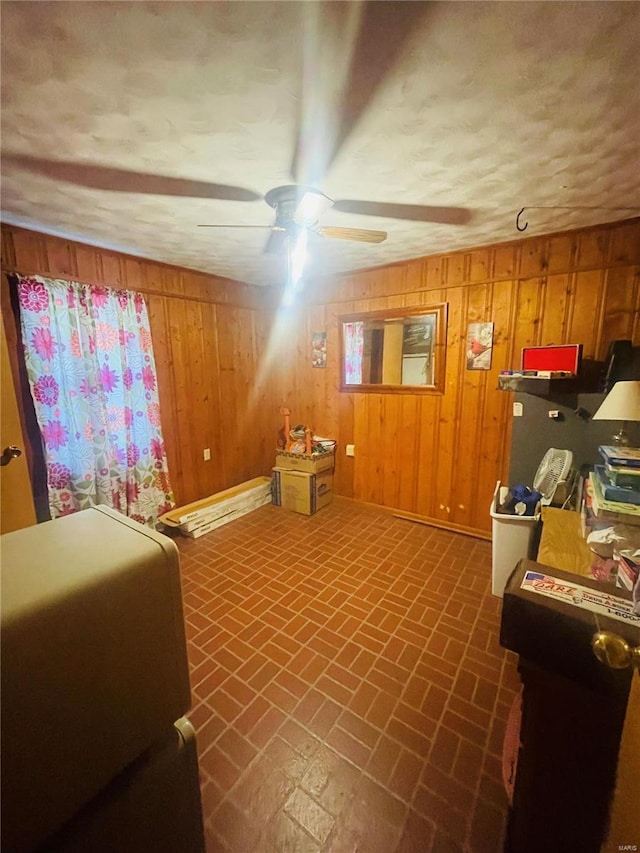 interior space with wooden walls and ceiling fan