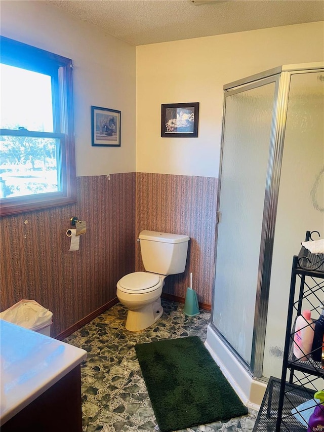 bathroom featuring a textured ceiling, vanity, toilet, and walk in shower