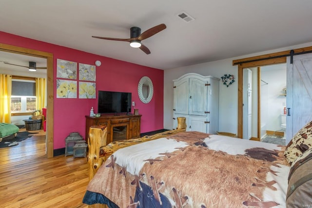 bedroom with ensuite bath, ceiling fan, light hardwood / wood-style flooring, and a barn door