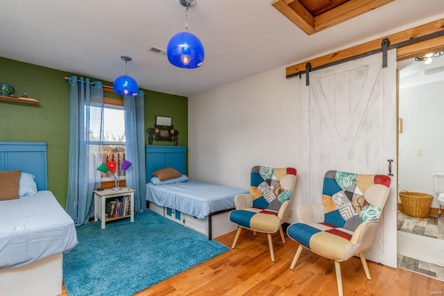 bedroom featuring a barn door and wood-type flooring