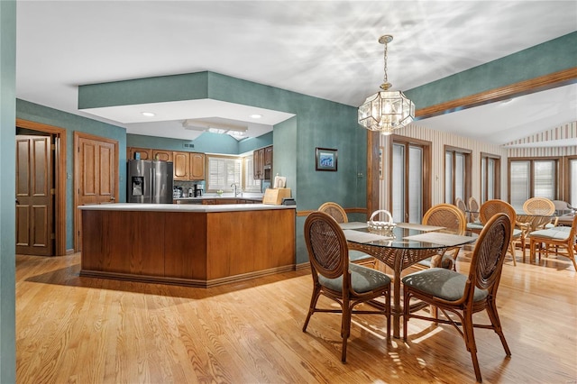 dining room featuring vaulted ceiling, sink, a notable chandelier, and light wood-type flooring