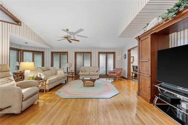 living room with ceiling fan, light hardwood / wood-style floors, and vaulted ceiling