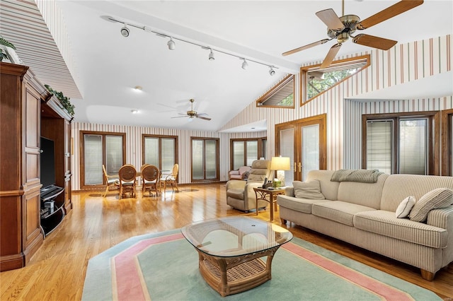 living room with ceiling fan, light hardwood / wood-style flooring, rail lighting, and vaulted ceiling