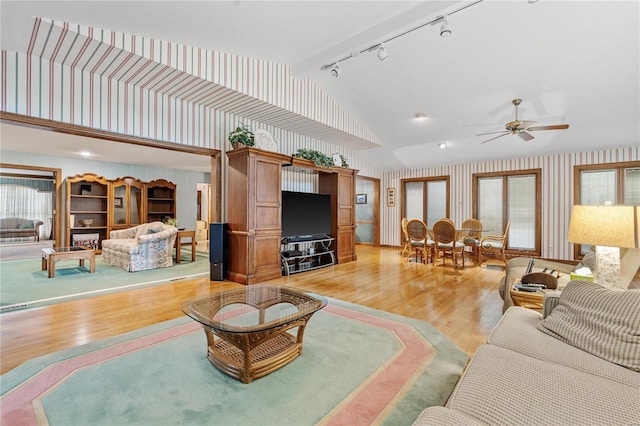 living room with hardwood / wood-style floors, track lighting, high vaulted ceiling, and ceiling fan