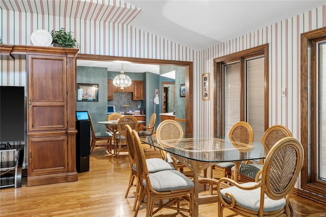 dining area with light hardwood / wood-style floors, lofted ceiling, and an inviting chandelier