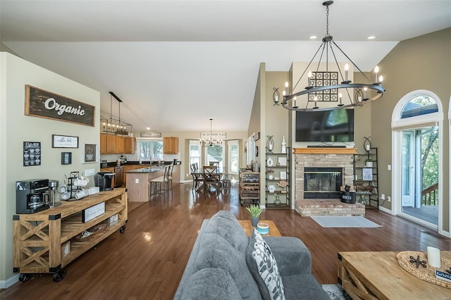 living room featuring dark hardwood / wood-style flooring, vaulted ceiling, a brick fireplace, and a healthy amount of sunlight