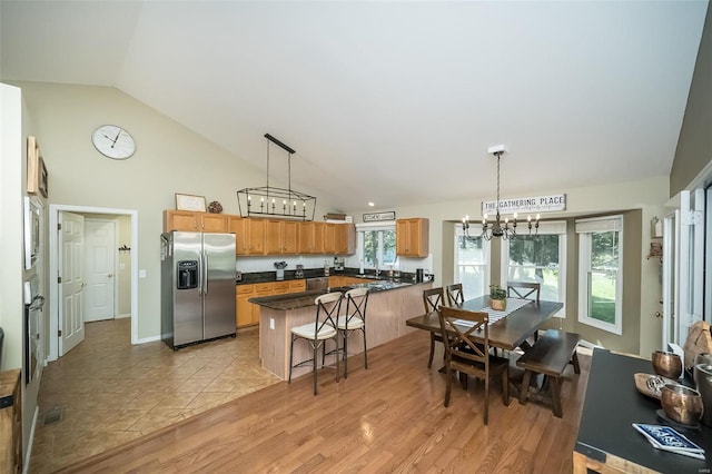 kitchen with hanging light fixtures, an inviting chandelier, a breakfast bar, appliances with stainless steel finishes, and light wood-type flooring